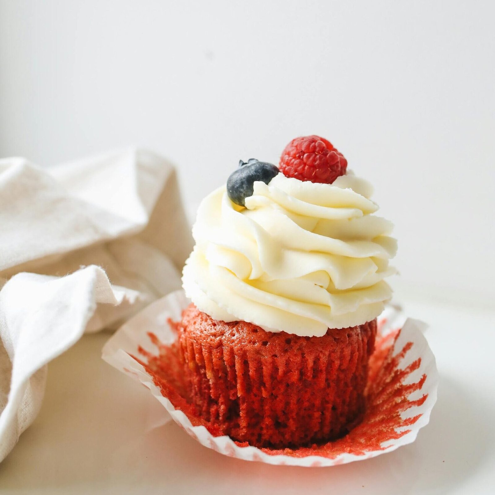 En stikk rød cupcake med vaniljakrem og skogbær