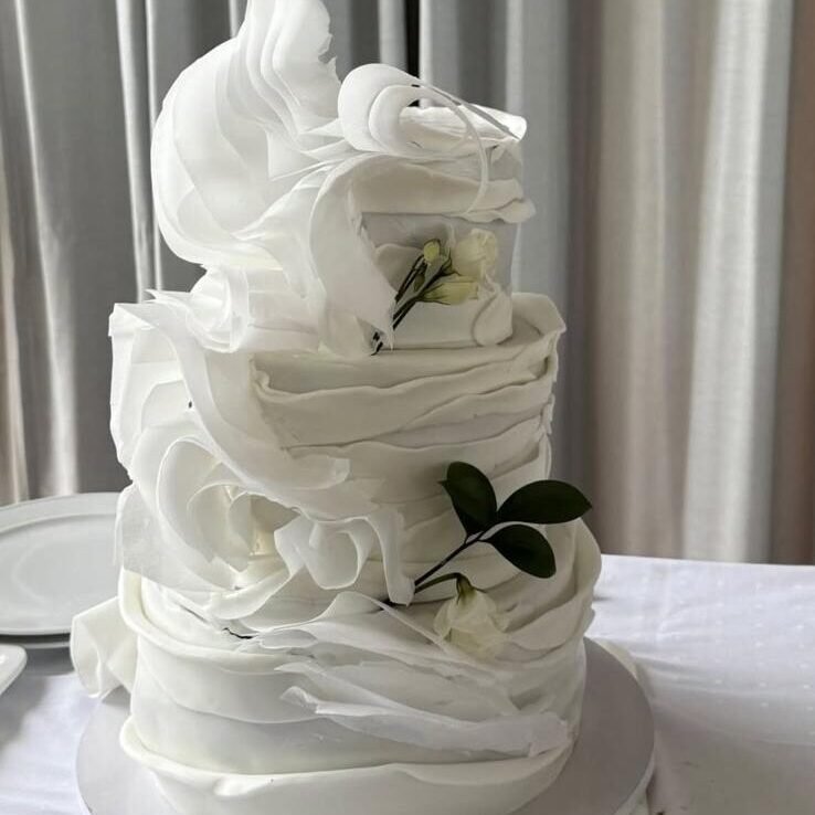 Et utvalg fargerike cupcakes utstilt på pastellfargede fat. Cupcakene er pyntet med rosa og hvit krem, dryss i ulike farger og sjokoladebiter. Noen har mørk sjokoladekakebunn, andre lys vaniljebunn.